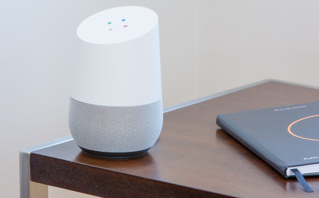 weiß und grau Google home auf braunem Tisch